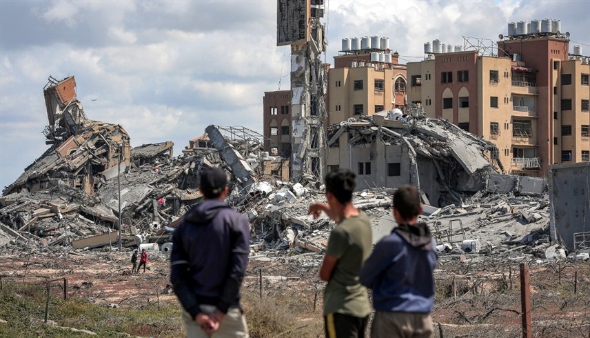 فلسطينيون يتفرجون على الدمار في مخيم النصيرات بغزة (أف ب)