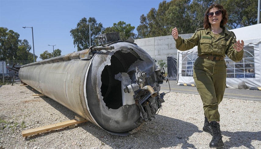 مجندة إسرائيلية تقف بجوار بقايا صاروخ إيراني بعد إسقاطه (إكس)