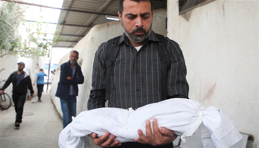 فلسطيني يحمل جثمان ابنه المقتول بغارة إسرائيلية على غزة (وكالات)