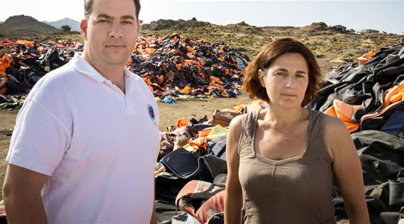 الناشطة إيفي لاتسودي وكوستانتينوس ميتراغاس من فريق الإنقاذ اليوناني أمام كومة هائلة من سترات النجاة في جزيرة ليسبوس (أرشيف)