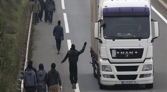 مهاجرون في كالي شمال فرنسا قرب شاحنة متجهة إلى بريطانيا عبر نفق المانش (أرشيف)