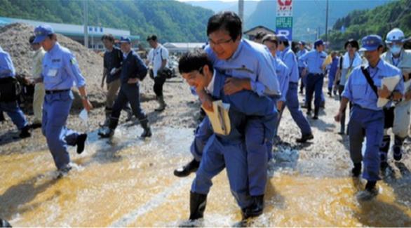 صورة متداولة للنائب الياباني وهو على ظهر مسؤول آخر عند اجتيازه لتجمع المياه(تويتر)