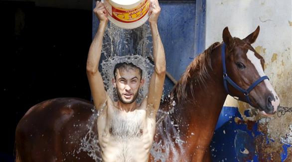 رجل يسكب الماء البارد على نفسه للتخفيف من حدة الحر في بيروت، لبنان (رويترز)