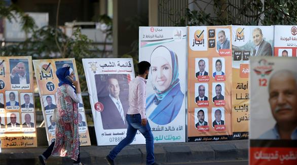 أردنيون يمرون بالقرب من إعلانات المرشحين في عمان (رويترز)