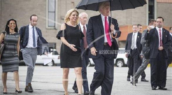 ترامب يسير تحت المظله وحده وخلفه النائب العام في فلوريدا (تويتر)