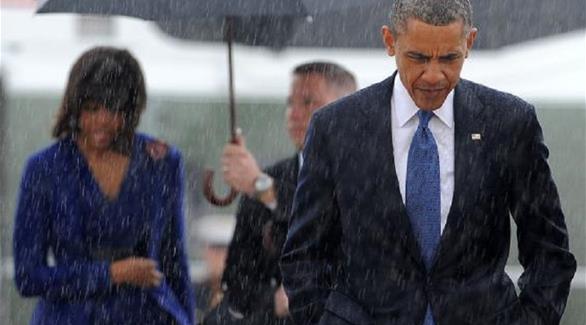 أوباما يسير تحت المطر معطياً مظلته لزوجته (تويتر)
