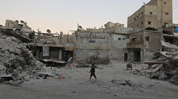صبي يمشي وسط أنقاض المباني المدمرة ضمن مناطق المعارضة في حلب (أ ف ب)