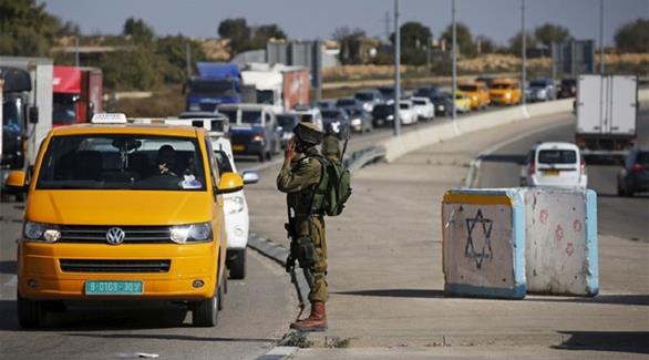 جندي إسرائيلي يوقف سرباً من المركبات الفلسطينية (أرشيف)