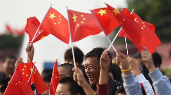 صينيون يحملون علم بلادهم في إحدى التجمعات في البلاد
