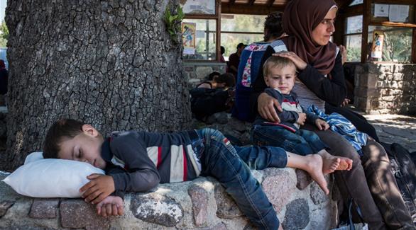 أم لاجئة تستريح مع طفليها بعد وصولهم إلى شواطئ جزيرة ليسفوس في اليونان (الأمم المتحدة)
