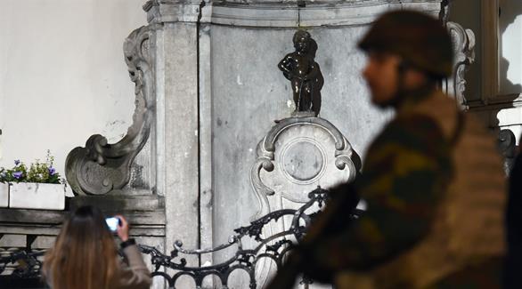 عنصر من الجيش البلجيكي يقف بجانب تمثال "مانيكان بيس" في بروكسل (أرشيف)