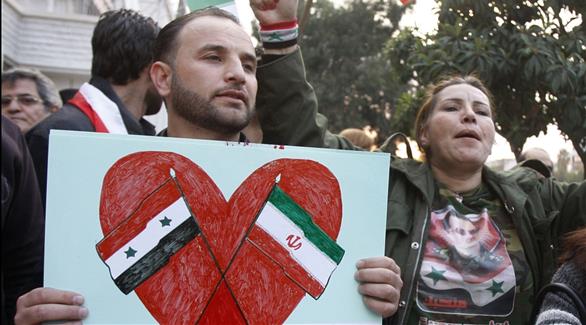 متظاهر يحمل العلمين السوري والإيراني (أرشيف)