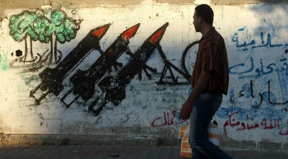 رجل فلسطيني يمر أمام غرافيتي لصواريخ (أبال ايماج)