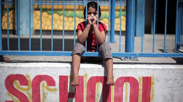 طفلة فلسطينية تجلس على حائط مدرسة "غزة الجديد" التابعة للأمم المتحدة بعد هروبها من القصف الإسرائيلي (أ ب)