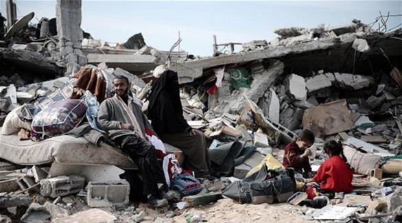 عائلة فلسطينية تجلس وسط ركام منزلها المدمر في العدوان الإسرائيلي على غزة 