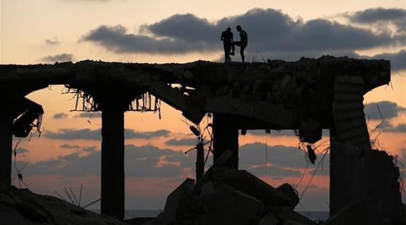 فلسطينيان فوق دمار غزة