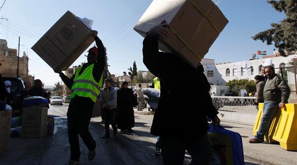 لاجئون سوريون يحملون مساعدات غذائية