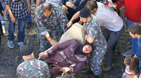 والدة أحد الجنود المختطفين من قبل داعش والنصرة أثناء إنقاذها بعد محاولة إشعال النيران في جسدها في بيروت (أرشيف)