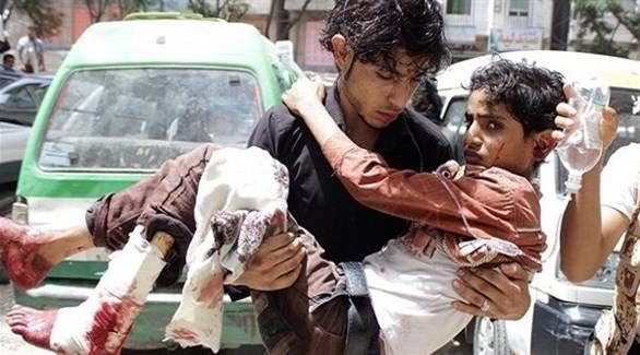 شاب يمني يحمل طفلاً مصاباً في تعز (أرشيف) 