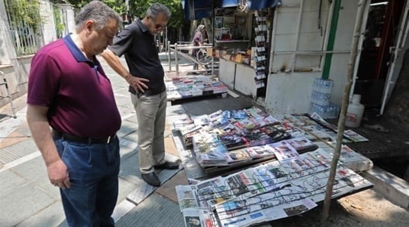 قراء يطالعون مجموعة من الصحف معروضة في شوارع طهران (غيتي)