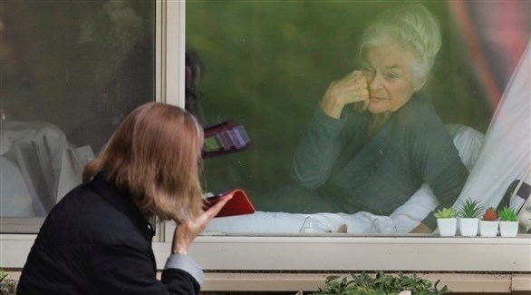 أمريكية تتفقد والدتها في مركز للرعاية من خلف النافذة في واشنطن.(أرشيف)
