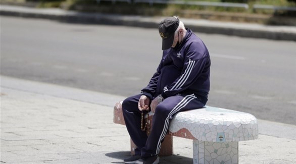 رجل يستريح على رصيف في شارع مقفر في زمن كورونا (أرشيف)