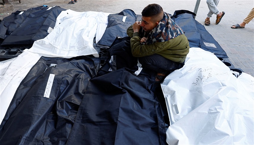 فلسطيني بين جثث عدد من ضحايا الحرب الإسرائيلية على غزة (وكالات)