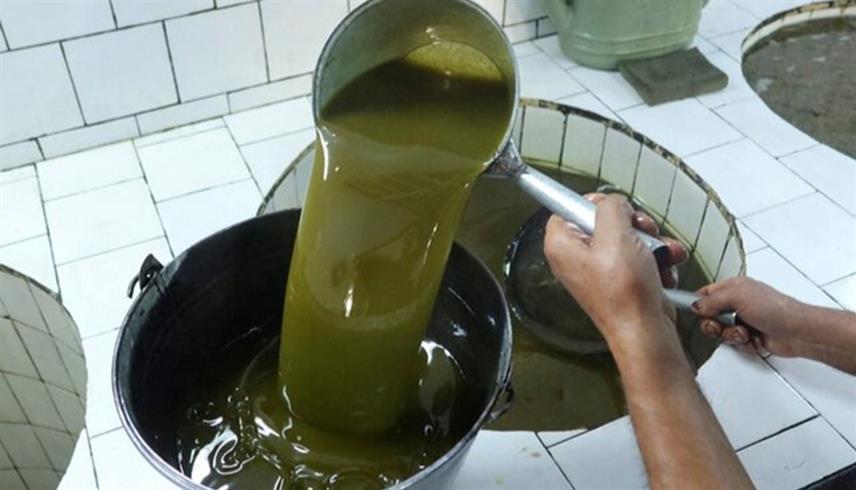 عامل يرشّح زيت الزيتون داخل معصرة في طبربة التونسية (رويترز)