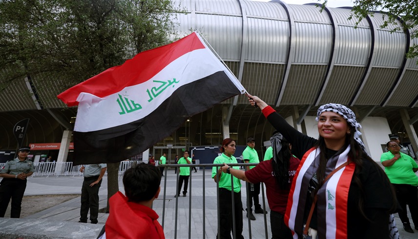 مشجعة عراقية ترفع علم بلدها (أ ف ب)