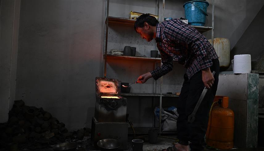 صائغ أفغاني يصهر الذهب في ورشة عمل بمدينة فيض آباد (أ ف ب)