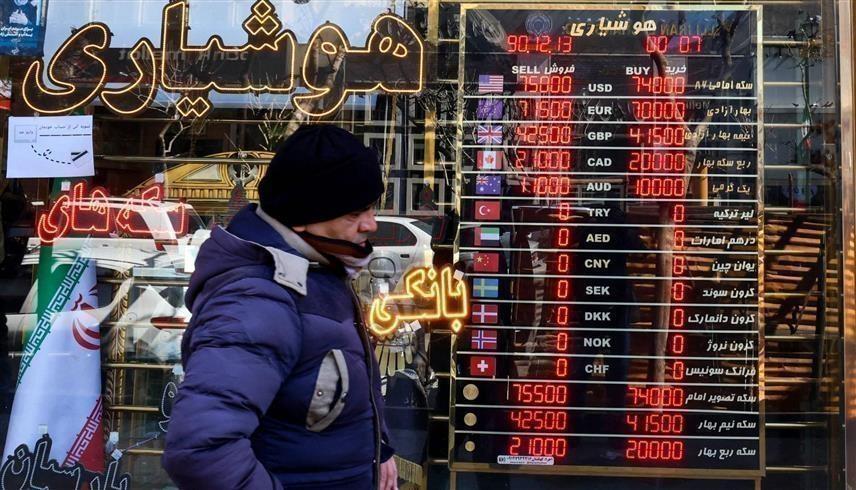 إيراني أمام لوحة تظهر سعر صرف الريال في طهران (أ.ب)