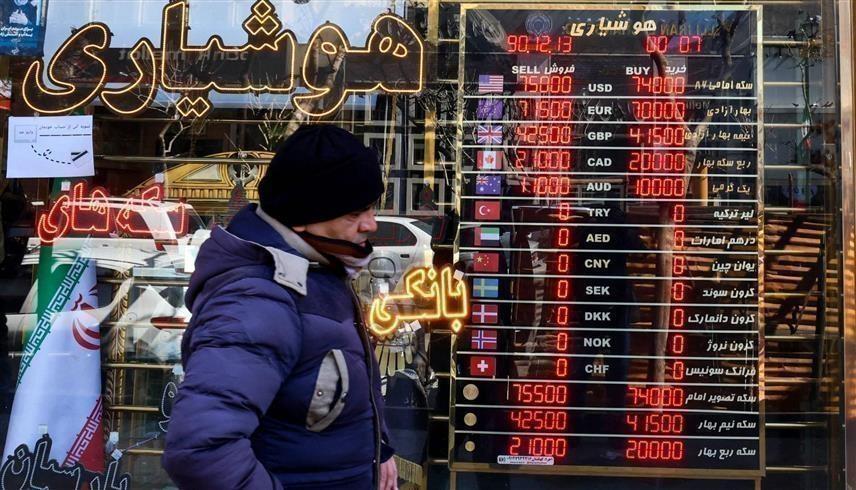 إيراني أمام لوحة تظهر سعر صرف الريال في طهران (أ.ب)