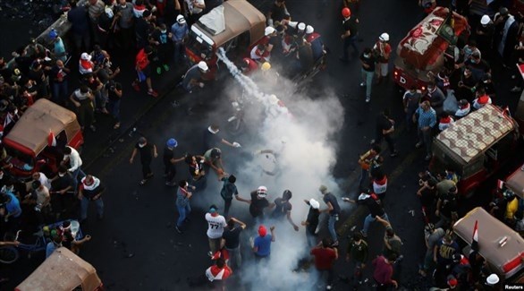 متظاهرون في بغداد يحاولون إخماد قنبلة مسيلة للدموع (أرشيف)