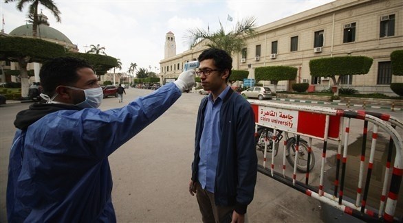 عامل صحي يتأكد من حرارة طالب أمام جامعة القاهرة في مصر(أرشيف)