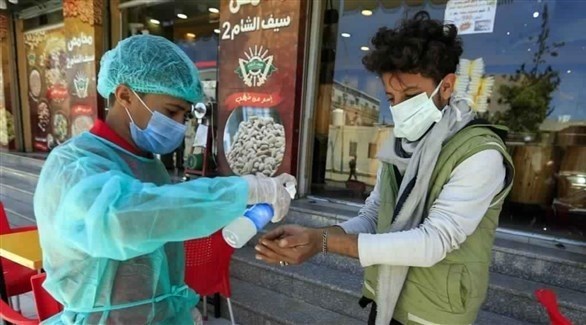 عامل صحي يساعد يمنياً على تعقيم يديه (أرشيف)