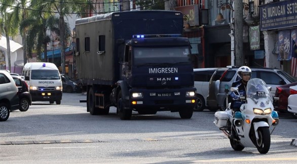 شرطي مرور ماليزي يتقدم شاحنة تقل مهاجرين لترحيلهم إلى ميانمار (تويتر)