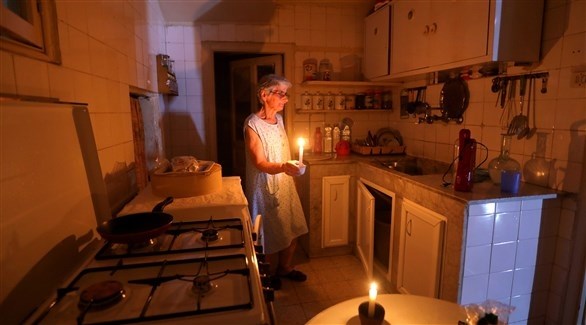 امرأة تتجول داخل منزلها وبيدها شمعة (أرشيف)
