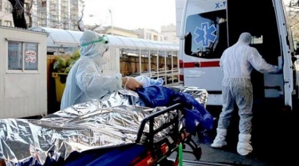 إيرانيان ينقلان مصاباً بكورونا إلى سيارة إسعاف (أرشيف)