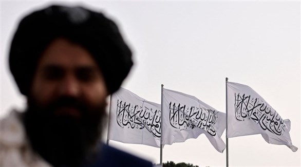 شخص يقف قبالة مجموعة من أعلام تنظيم طالبان (أرشيف)