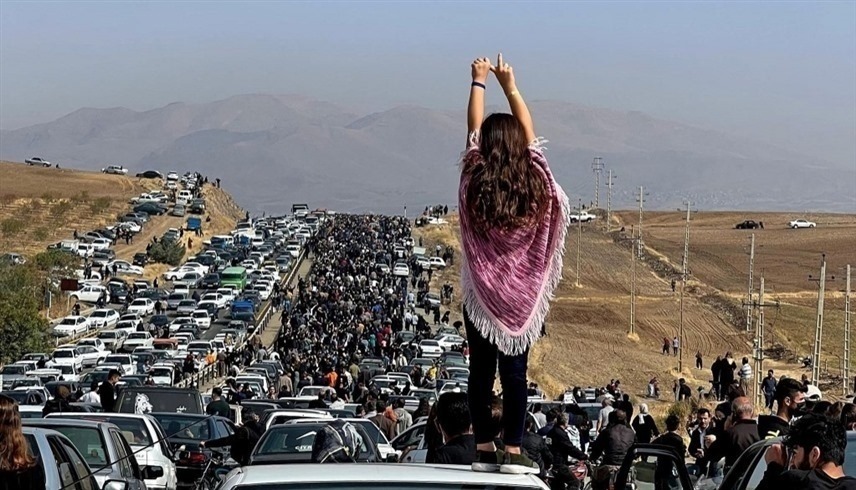 إيرانية تقف على سقف سيارة أمام مواطنين في طريقهم إلى مسقط مهسا أميني.(أف ب)