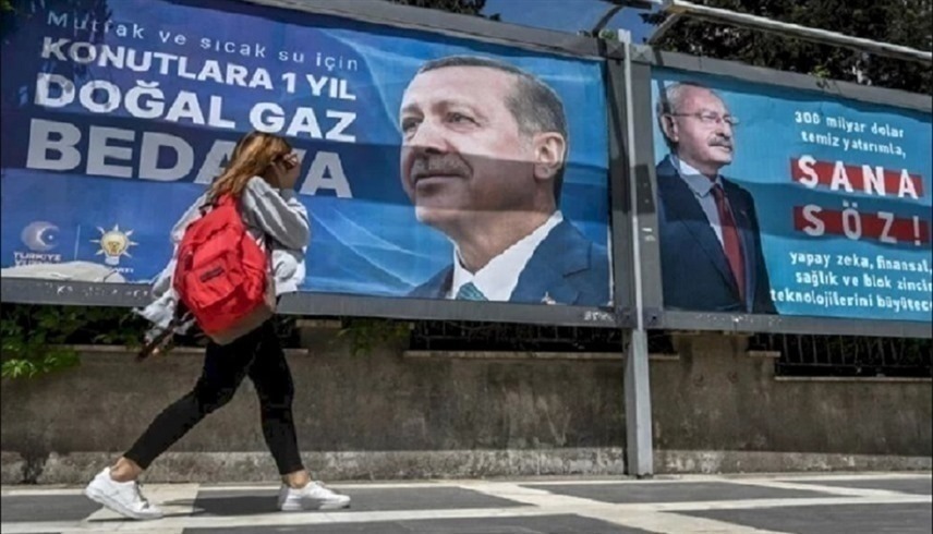 تركية أمام لافتتين انتخابيتن لمرشح المعارضة كمال كليتشدار أوغلو والرئيس التركي رجب طيب أردوغان (أرشيف)